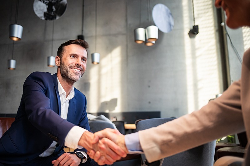 A man shaking hands with another while smiling