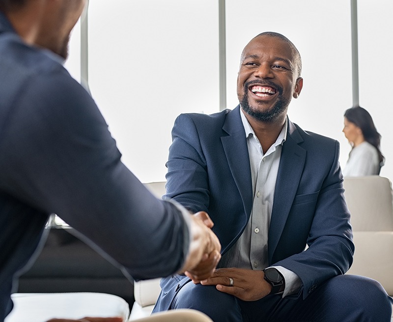 A man smiling while shaking hands with another