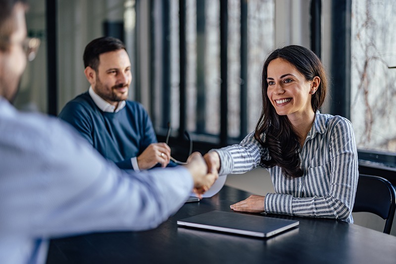 A woman happily shakes the hands of a man